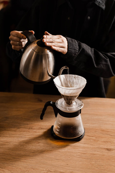 フィルターコーヒーの代替醸造方法を注ぎなさい。紙フィルターに含まれる焙煎・挽いたコーヒー豆にお湯をかける - 写真・画像
