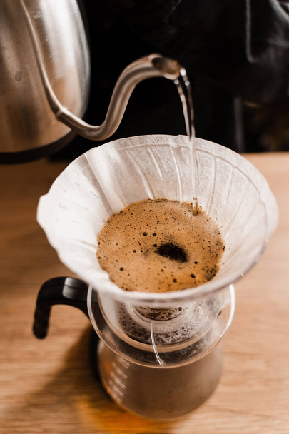 Kaada suodatin kahvi vaihtoehtoinen panimomenetelmä. Kuuman veden kaataminen paahdettujen ja jauhettujen kahvipapujen päälle paperisuodattimessa - Valokuva, kuva