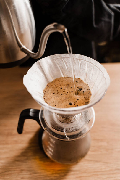 Nalijte přes filtr s mletou kávou v nálevce v ohnisku. Vaří se káva s filtrem. Nalijte přes alternativní způsob nalévání vody na pražená a mletá kávová zrna obsažená ve filtru - Fotografie, Obrázek