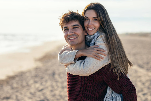 Portrait of beautiful young couple in love enjoying the day in a cold winter on the beach. - Фото, зображення