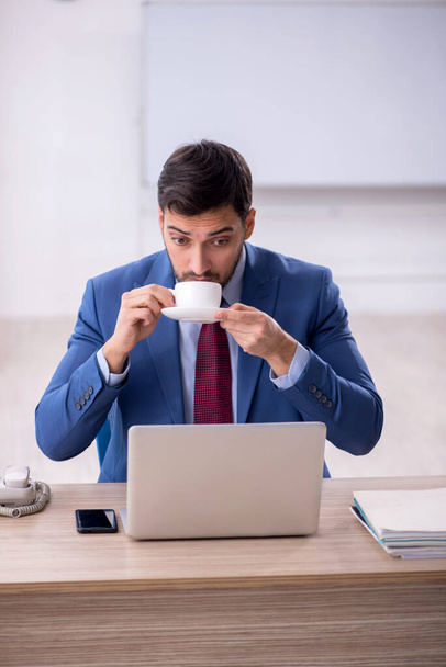 Empleado joven que bebe café en el lugar de trabajo - Foto, imagen