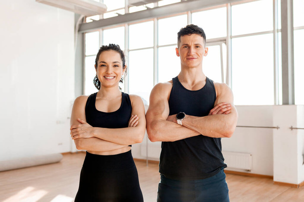 beautiful athletic couple in sportswear stands in the gym in the morning, fitness girl and coach man in training in bright room - Photo, Image