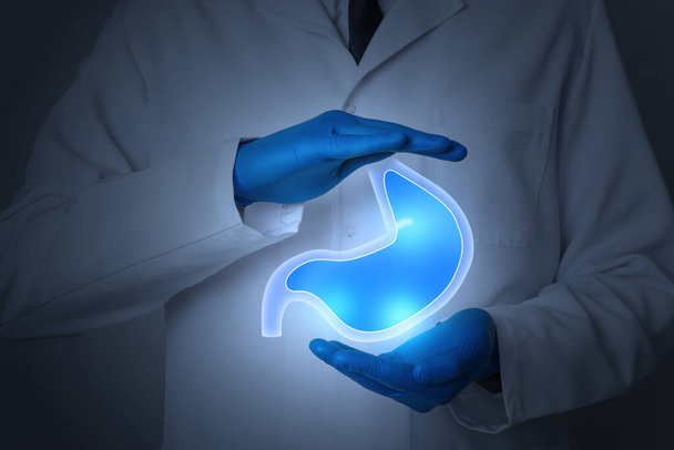 Symptoms and treatment of heartburn and other gastrointestinal diseases. Doctor holding stomach illustration on dark background, closeup - Fotó, kép