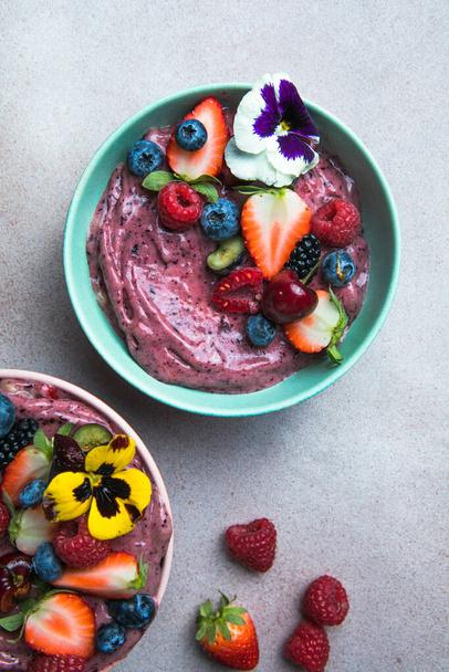 Δύο καλοκαιρινά μπολ smoothie acai με φράουλες, βατόμουρα, σε γκρι μπετόν φόντο. Φιάλη πρωινού με φρούτα και δημητριακά, close-up, top view, υγιεινή διατροφή - Φωτογραφία, εικόνα