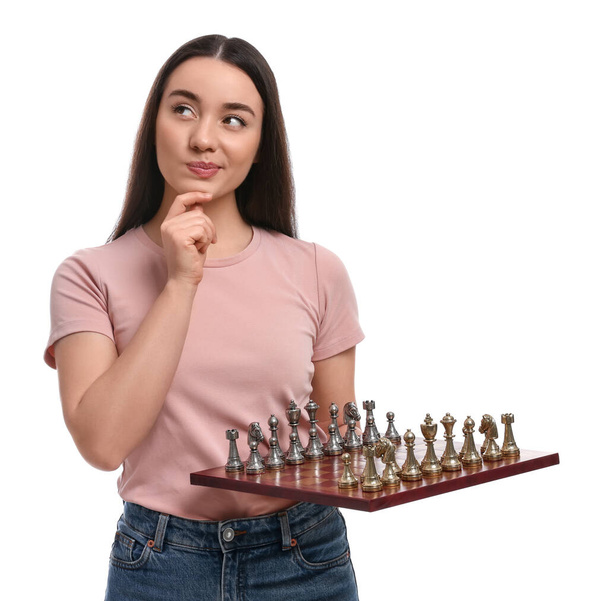 Thoughtful woman holding chessboard with game pieces on white background - Foto, imagen