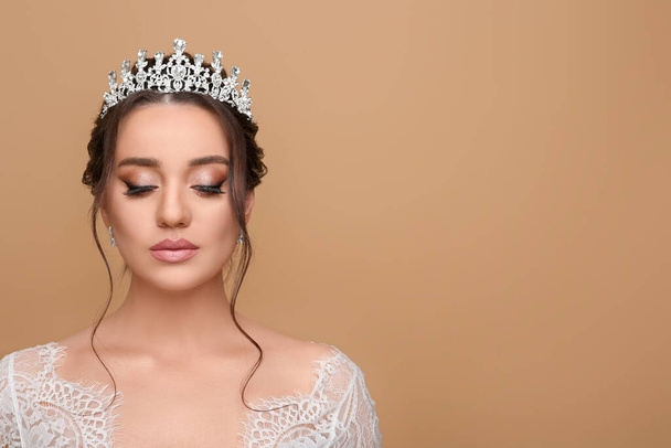 Beautiful young woman wearing luxurious tiara on beige background, space for text - Фото, зображення