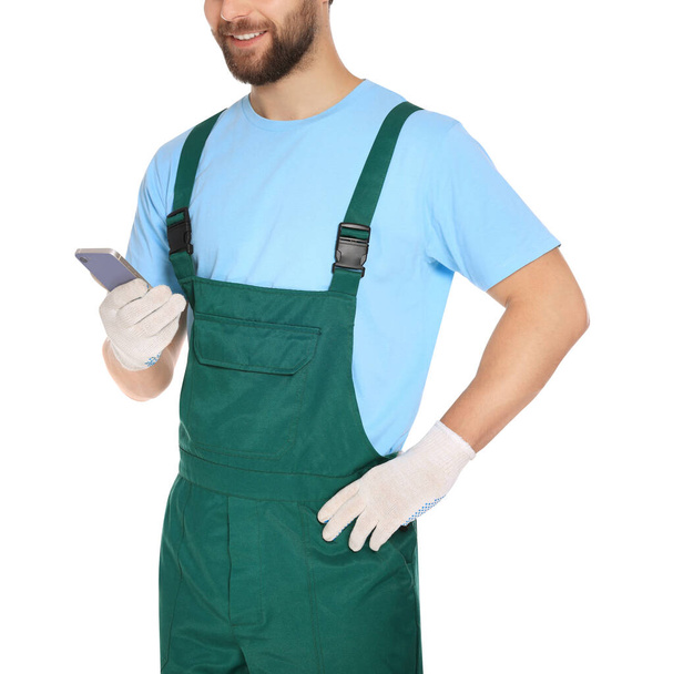 Professional repairman in uniform with smartphone on white background, closeup - Foto, imagen