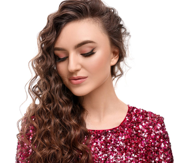 Beautiful young woman with long curly brown hair in pink sequin dress on white background - Фото, изображение