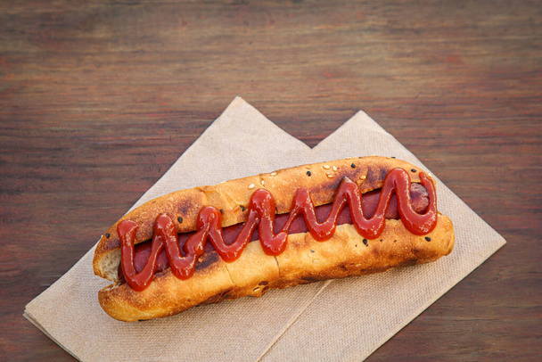 Fresh tasty hot dog with ketchup on wooden table - Fotó, kép