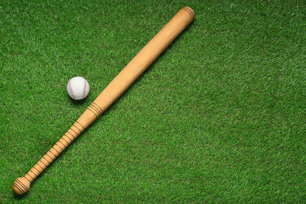Wooden baseball bat and ball on green grass, flat lay. Space for text - Fotoğraf, Görsel