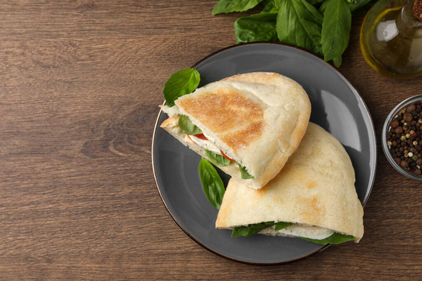 Delicious pita sandwiches with mozzarella, tomatoes and basil on wooden table, flat lay. Space for text - Fotografie, Obrázek