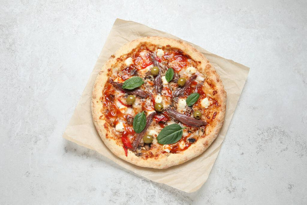 Tasty pizza with anchovies, basil and olives on white table, top view - Foto, Bild