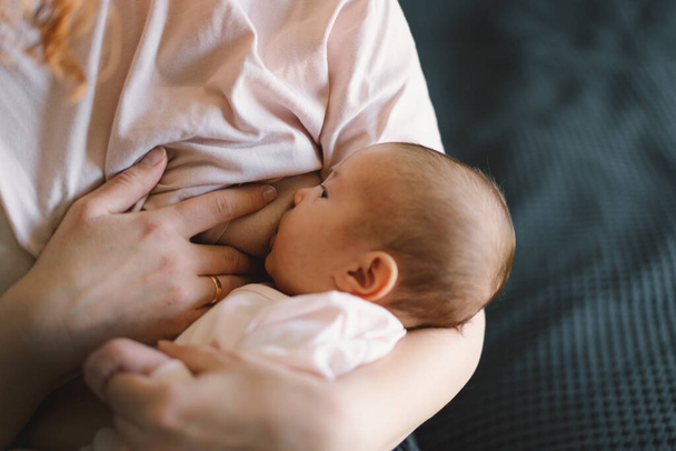 Newborn baby girl sucking milk from mothers breast. Portrait of mom and breastfeeding baby. Concept of healthy and natural baby breastfeeding nutrition. - Fotó, kép