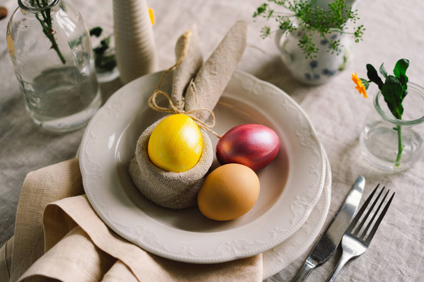 Buona Pasqua. Eleganti uova di Pasqua su un tovagliolo con fiori primaverili su sfondo di legno bianco. Apparecchiare. Il concetto di una felice vacanza pasquale. - Foto, immagini