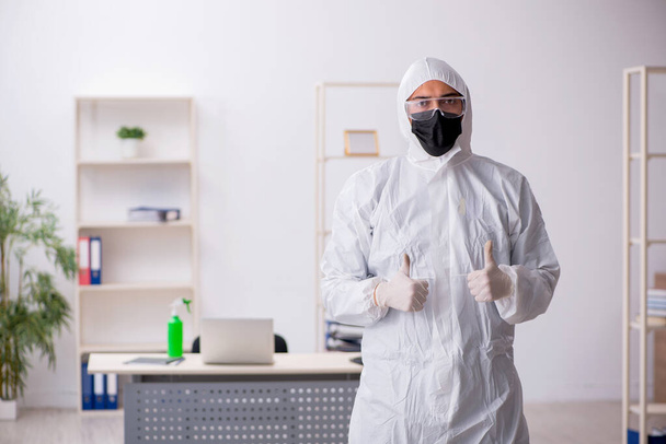 Young contractor disinfecting office during pandemic - Foto, imagen