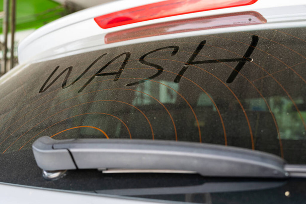 Schmutzige hintere Scheibe des Autos und Aufschrift Wash. Wash Text on Dirty Car. - Foto, Bild