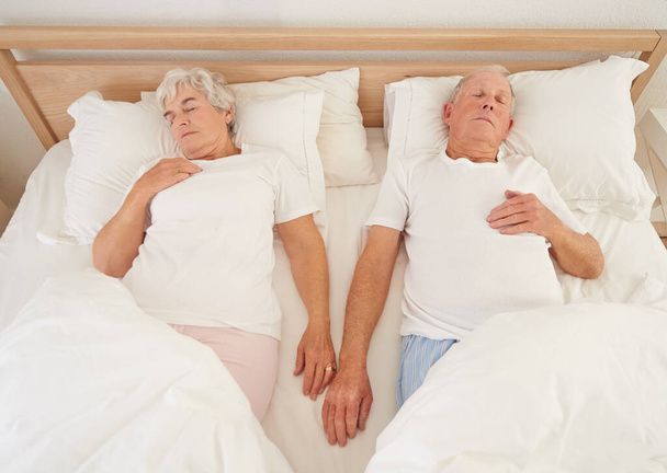 共生の生涯。ベッドの中で眠っている高齢者のカップルの高角度ショット - 写真・画像