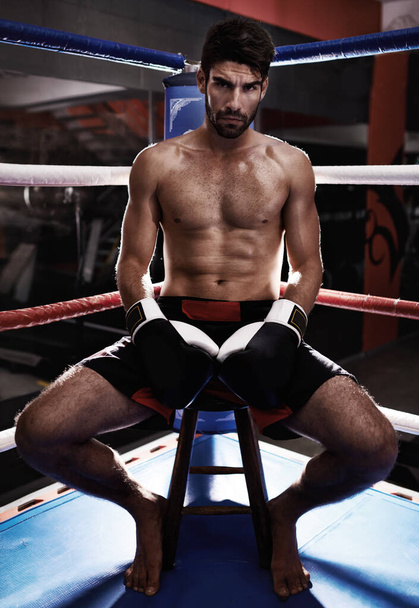 Victor je v rohu. Odhodlaný boxer s nahou hrudí sedící v rohu boxerského ringu - Fotografie, Obrázek