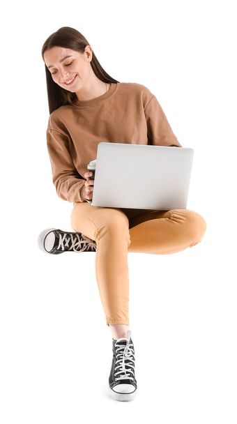 Jolie jeune femme avec ordinateur portable assis sur une chaise sur fond blanc - Photo, image