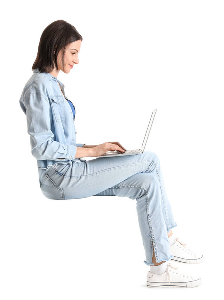 Pretty young woman with laptop sitting on chair against white background - 写真・画像