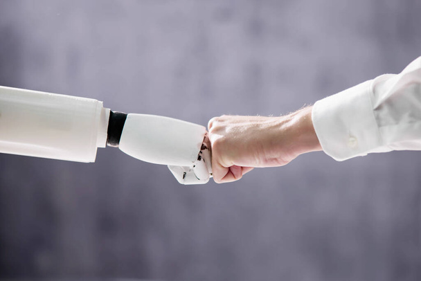 Robot And Human Hand Making Fist Bump On Grey Background - Foto, Imagem