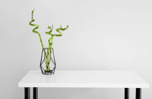 Vase with bamboo plant on table near grey wall - 写真・画像
