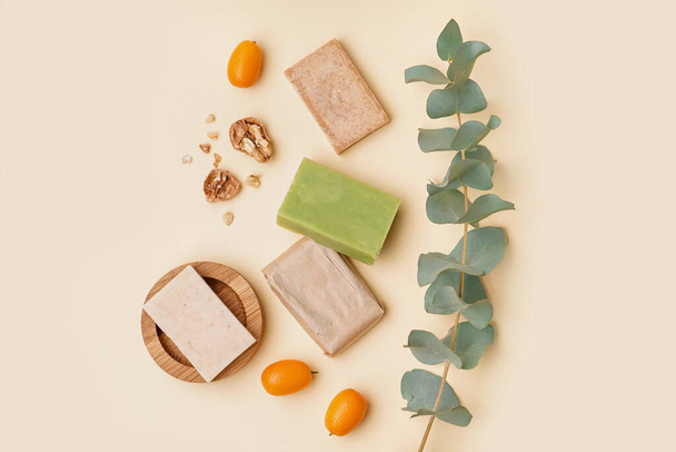 Composition with natural soap bars, eucalyptus branch, kumquat and walnut on color background - Foto, afbeelding