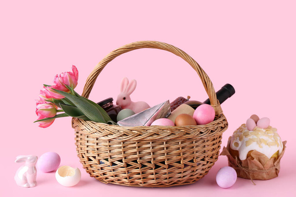 Koszyk z jajkami wielkanocnymi, kwiatami tulipanów i butelką wina na różowym tle - Zdjęcie, obraz