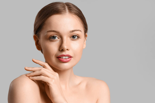 Pretty young woman with healthy skin  on grey background - Foto, afbeelding