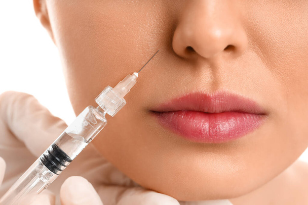 Young woman receiving filler injection in face, closeup - Foto, afbeelding