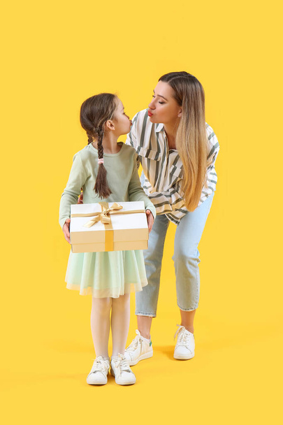 可愛いです女の子とともに彼女の母とギフト上の黄色の背景 - 写真・画像