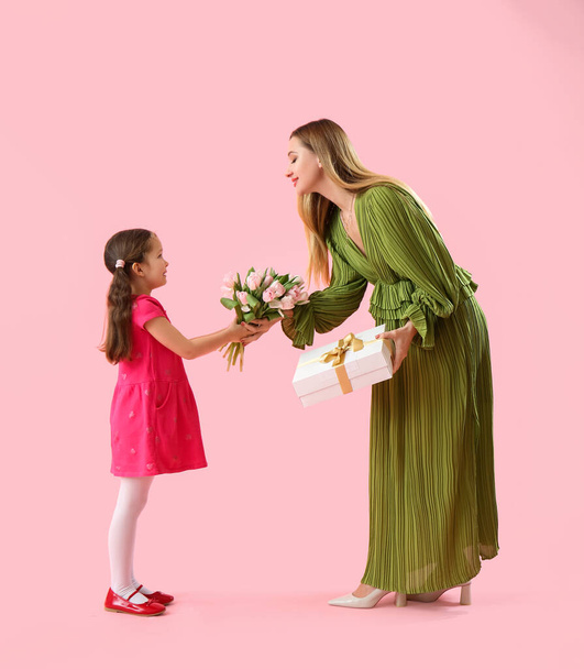 Söpö pieni tyttö tervehtii äitiään vaaleanpunaisella taustalla - Valokuva, kuva
