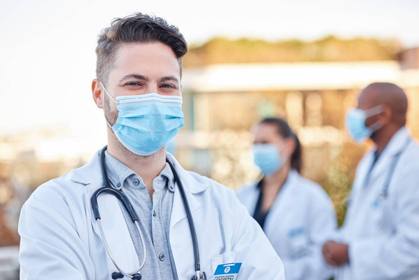 Face mask, covid doctor and man portrait outdoor with arms crossed for medical and health insurance. A happy healthcare worker with ppe for corona virus safety and compliance for wellness and help. - Foto, Imagen
