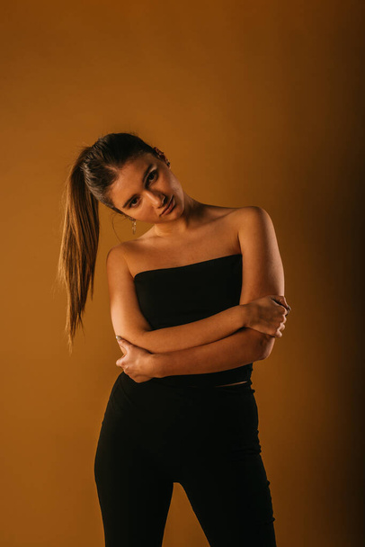 Σέξι νεαρή κοπέλα με μαύρα ρούχα που δείχνει σαγηνευτικά - Φωτογραφία, εικόνα