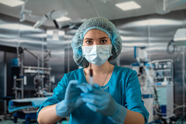 Ελκυστική γυναίκα γιατρός κρατώντας σύριγγα στο χειρουργείο για τον ασθενή. Φάρμακα. σύριγγα ιατρών χειρουργείου στα χέρια - Φωτογραφία, εικόνα