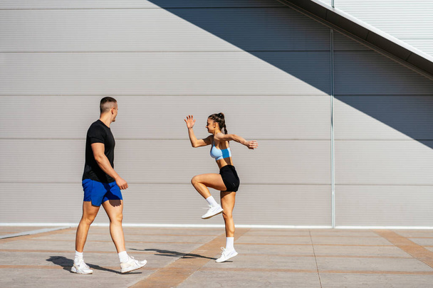 Un hombre fuerte está mirando a su novia mientras ella está corriendo lentamente y haciendo pequeños saltos - Foto, Imagen