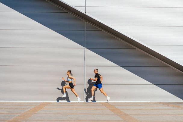 Allenamento di coppia sportiva muscolare insieme in una giornata di sole. Stanno facendo jogging. - Foto, immagini