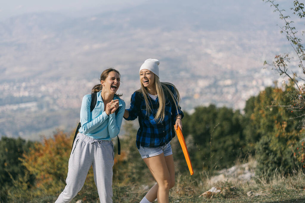 山の中でハイキングをしながらとても楽しい会話をしている2人の女の子。彼らは大声で笑っている - 写真・画像