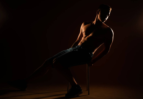 Handsome man sitting on the chair at the studiio - Foto, Imagen