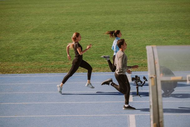 Three friends running on a blue sports track - Photo, Image
