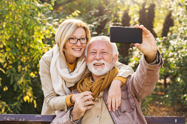 Seniorenpaar benutzt Handy im Park  - Foto, Bild