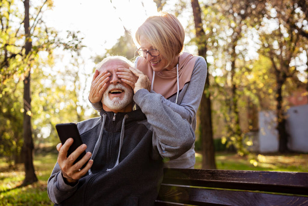 senior couple using phone in park  - Foto, Bild