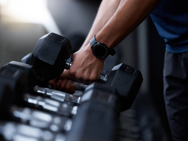 Fitness, dumbbell and hands of man at gym with smart watch for training, tracker or workout app. Strong, muscle and weightlifting with wearable tech on bodybuilder for sport, exercise or goal. - 写真・画像