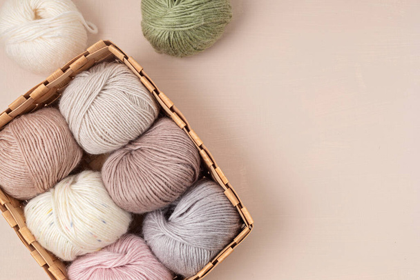 Craft knitting hobby background with yarn in natural colors. Recomforting hobby to reduce stress for cold fall and winter weather. Mock up, copy space, top view - Fotó, kép