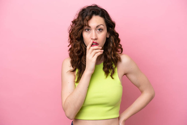 Young caucasian woman isolated on pink background surprised and shocked while looking right - Fotó, kép