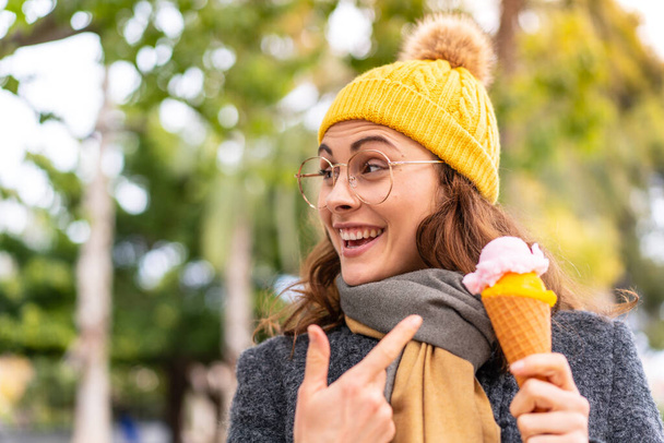 Brunette woman with a cornet ice cream at outdoors - Фото, изображение