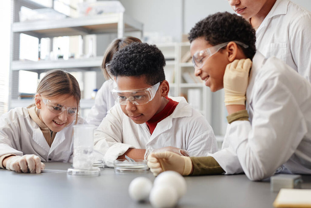 Porträt eines afroamerikanischen Jungen genießt naturwissenschaftliche Experimente im Chemieunterricht und trägt Schutzkleidung - Foto, Bild
