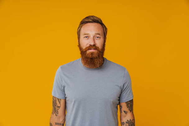 Bearded happy man posing at camera while standing isolated over yellow background - Foto, Imagen