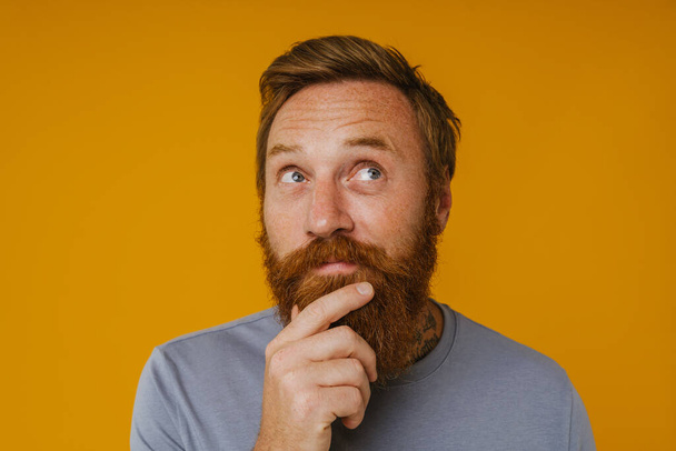 Bearded happy man posing at camera while standing isolated over yellow background - Foto, immagini