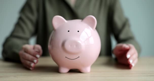 Frau umarmt rosa Sparschwein mit Münzen Nahaufnahme 4k Film Zeitlupe. Finanzierungskonzept retten - Filmmaterial, Video